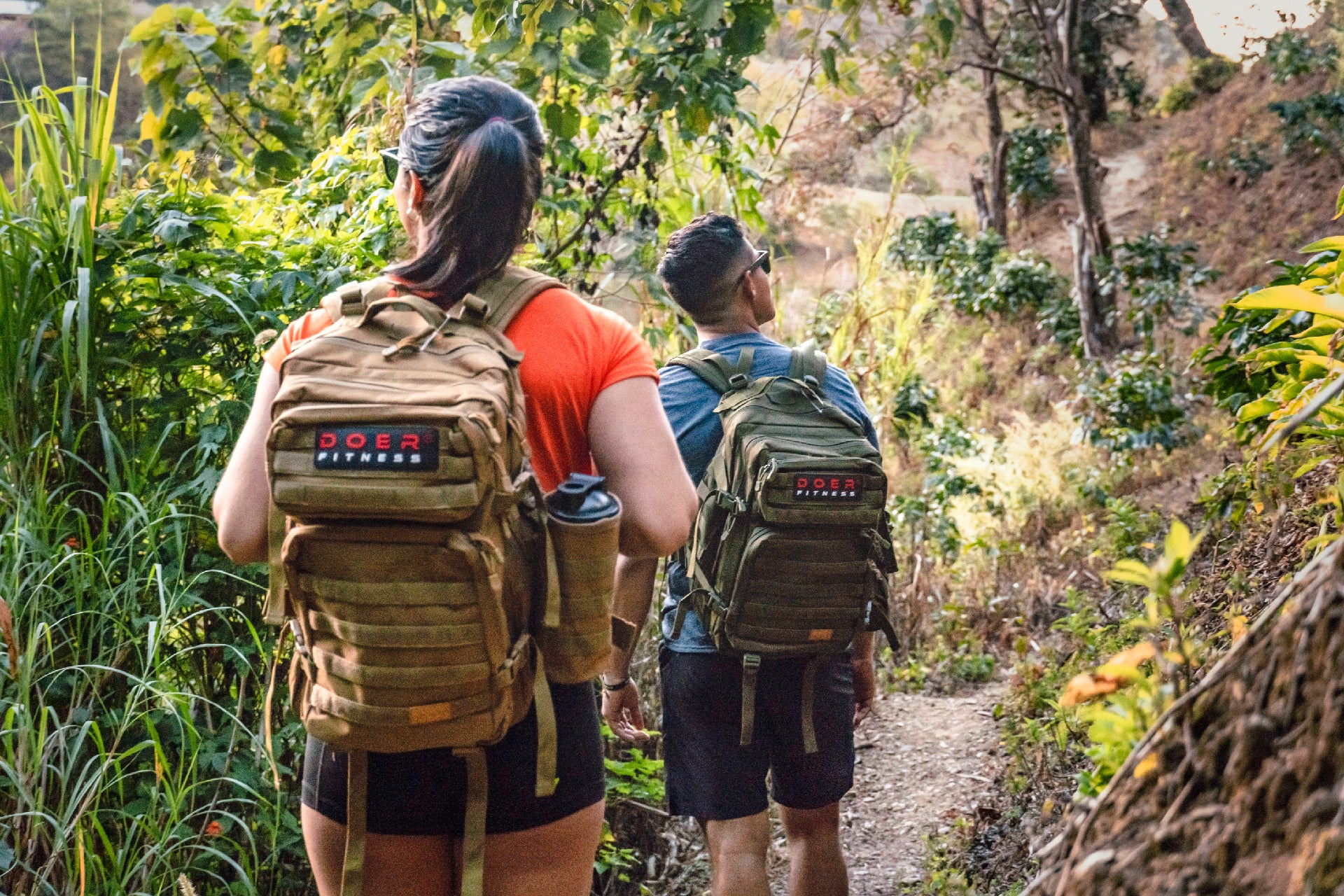 Two hikers wearing DOER tactical backpacks on a scenic hiking trail in Costa Rica.